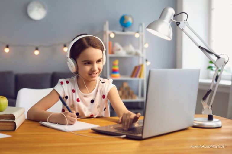 anak sedang belajar daring di depan laptop menggunakan headphone