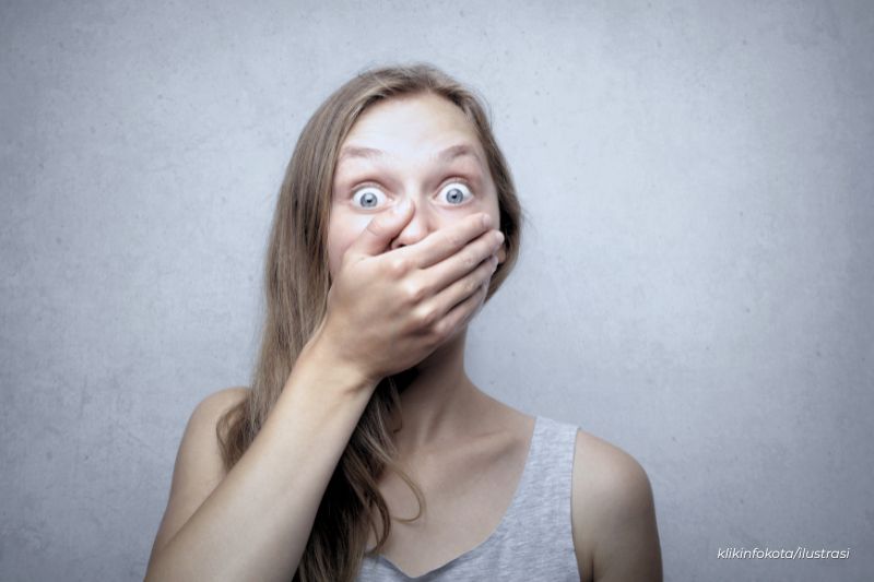 wanita menutup mulut terkejut
